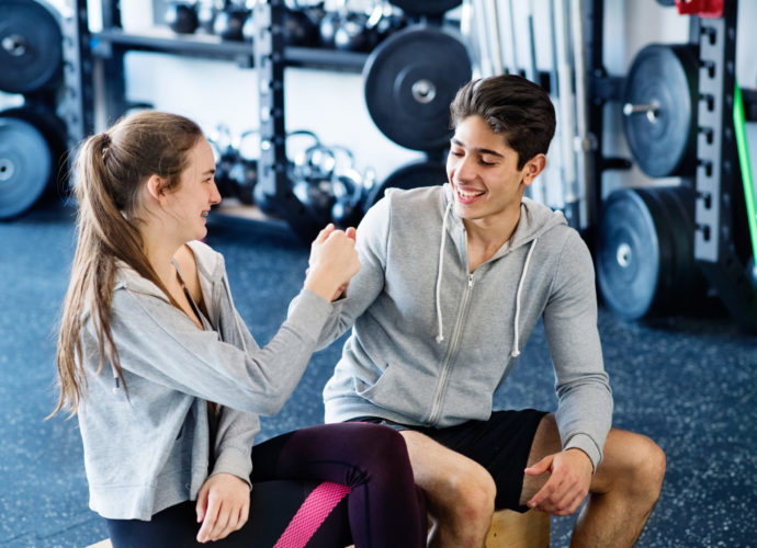 Young fit couple in crossfit gym doing fist pump.